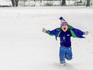 Kleiner Junge rennt laut rufend durch den Schnee